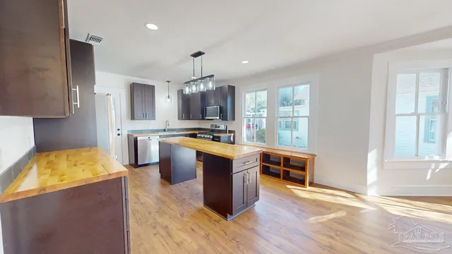 a large kitchen with kitchen island granite countertop wooden floors and stainless steel appliances