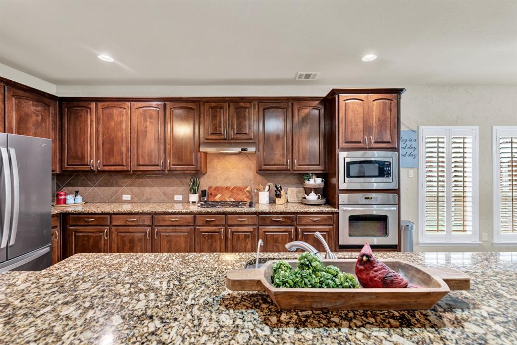 1701 Meadow Ranch Road McKinney, TX 75071 - Photo 15 of 40 a kitchen with stainless steel appliances granite countertop a refrigerator oven stove sink and cabinets