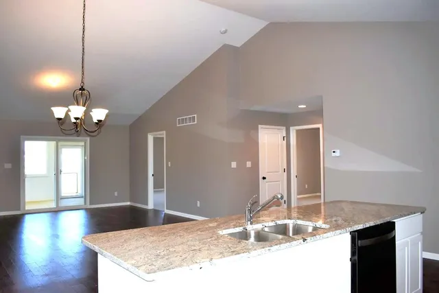 a kitchen with granite countertop a sink cabinets and wooden floor