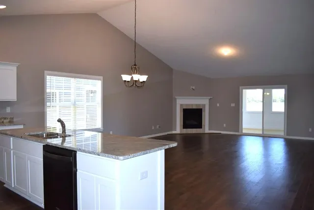 a large kitchen with granite countertop a large counter top a sink stainless steel appliances and cabinets