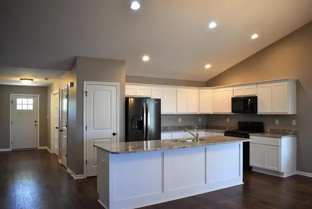 a kitchen with stainless steel appliances granite countertop a refrigerator and a stove top oven
