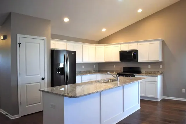 a kitchen with stainless steel appliances granite countertop a refrigerator and a stove top oven