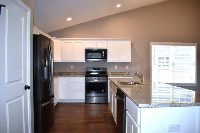 a kitchen with granite countertop a sink a stove and refrigerator