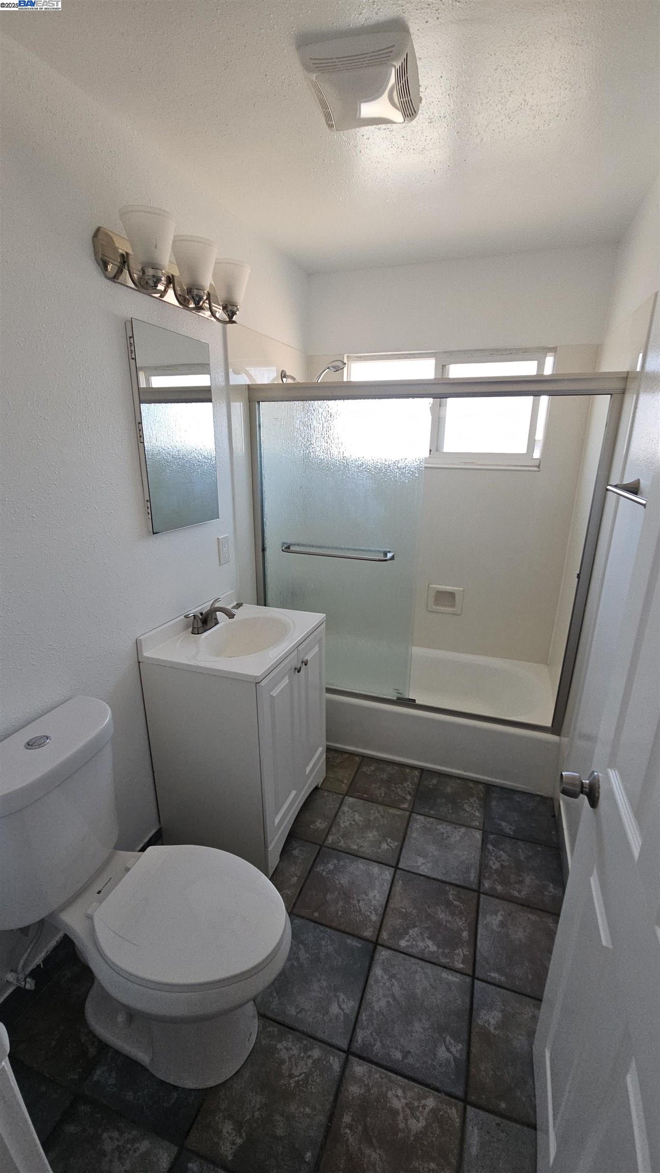 7448 Lockwood Street Oakland, CA 94621 - Photo 11 of 35 a bathroom with a toilet a sink and mirror