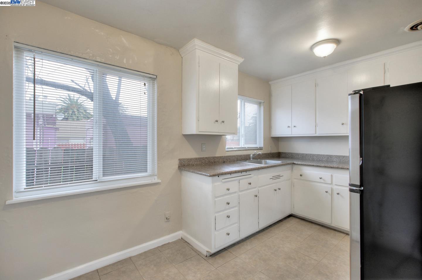 7448 Lockwood Street Oakland, CA 94621 - Photo 18 of 35 a kitchen with granite countertop white cabinets and a refrigerator