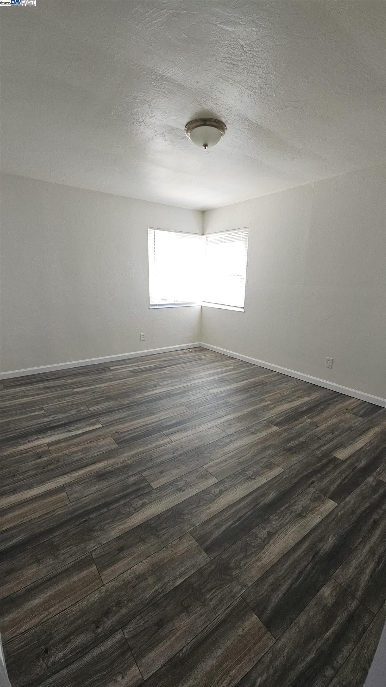 7448 Lockwood Street Oakland, CA 94621 - Photo 10 of 35 a view of an empty room with wooden floor and a window