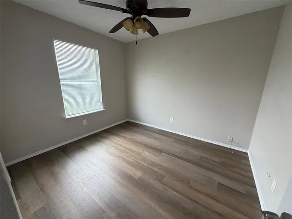 an empty room with wooden floor cabinet and windows