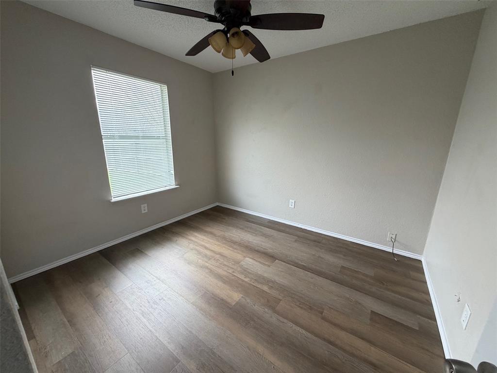 7401 Wagonwheel Road Fort Worth, TX 76133 - Photo 7 of 9 an empty room with wooden floor cabinet and windows