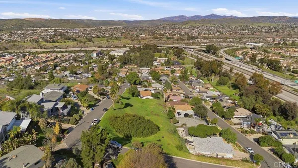 an aerial view of residential houses with outdoor space and trees