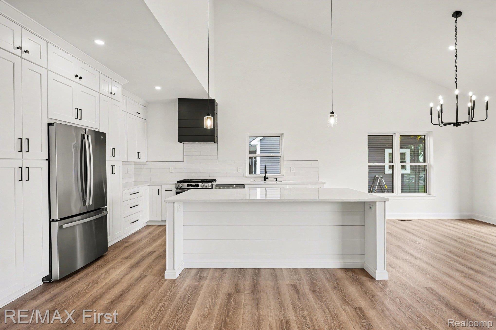 7424 Dyke Road Algonac, MI 48001 - Photo 14 of 31 Kitchen with stainless steel appliances, white cabinets, light wood-type flooring, tasteful backsplash, and vaulted ceiling