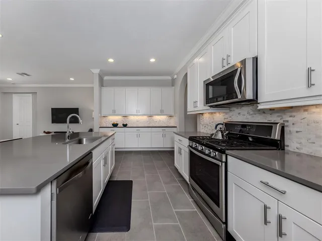 a kitchen with stainless steel appliances granite countertop a sink a stove top oven a counter space and cabinets