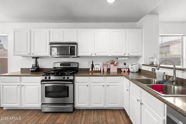 a kitchen with stainless steel appliances granite countertop a sink and cabinets with wooden floors
