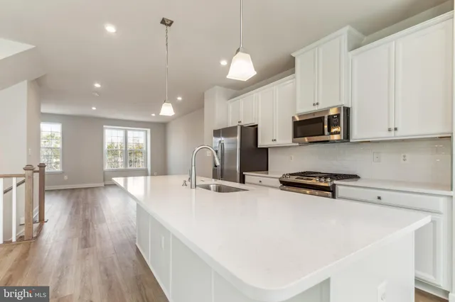 a kitchen with stainless steel appliances a stove a sink a microwave a center island and cabinets