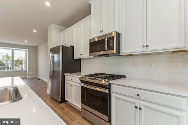 a kitchen with stainless steel appliances white cabinets and a stove top oven