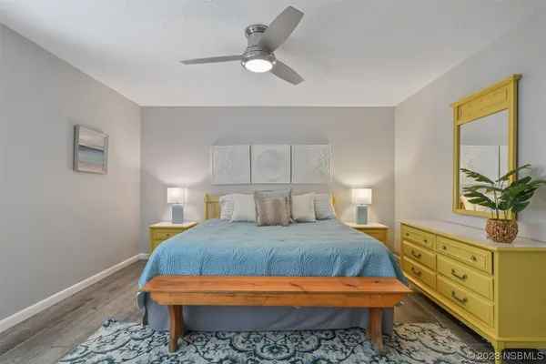 a bedroom with a bed and a potted plant on the dresser