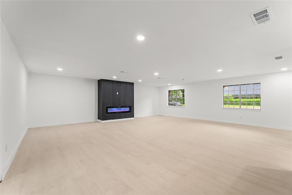 110 Hackberry Street Lancaster, TX 75146 - Photo 11 of 32 Spacious room featuring light wood-finish flooring, recessed lighting, and a dark accent wall with a built-in electric fireplace