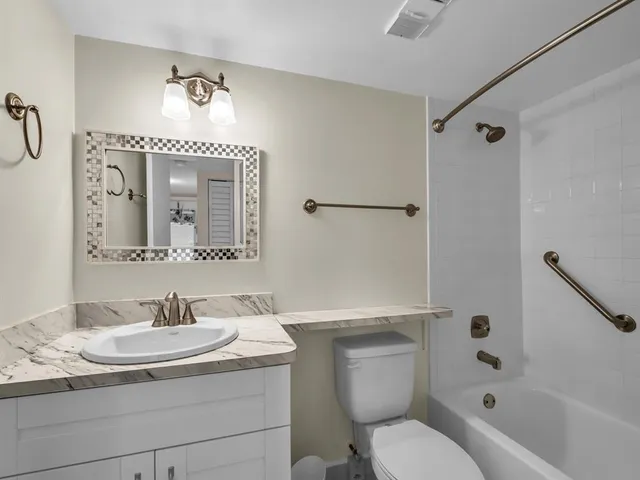 a bathroom with a granite countertop toilet sink and a mirror