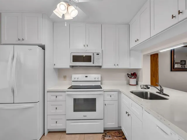 a kitchen with white cabinets and white appliances