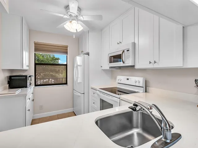 a kitchen with stainless steel appliances a white stove top oven a sink a refrigerator and white cabinets
