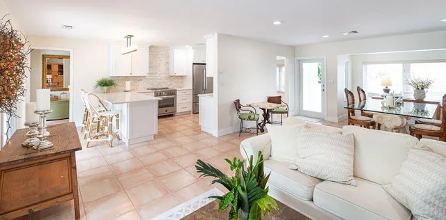 a living room with furniture potted plant and kitchen view