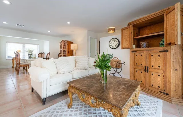 a living room with furniture a clock and a view of kitchen