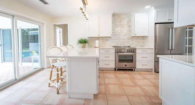 a kitchen with stainless steel appliances a stove a sink and white cabinets