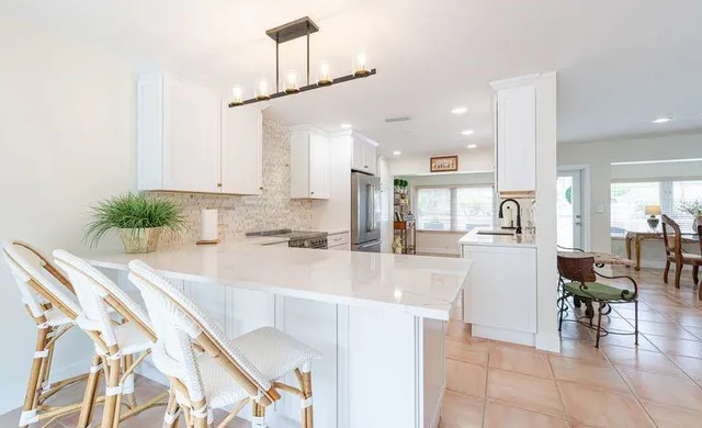 a kitchen with stainless steel appliances kitchen island granite countertop a table and chairs in it
