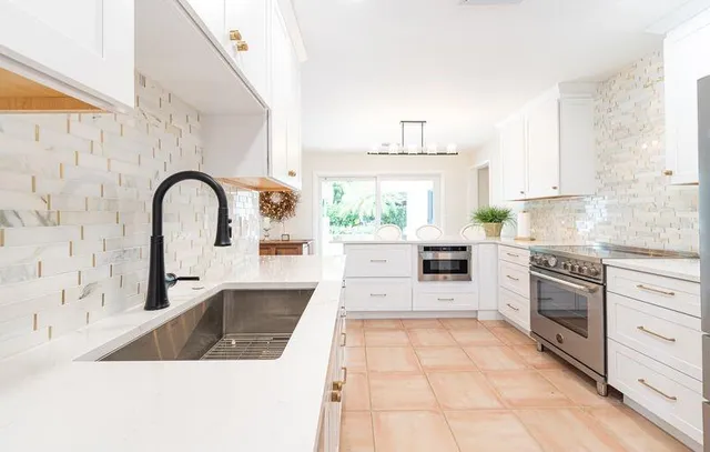 a kitchen with granite countertop a stove a sink and a stove with wooden floors