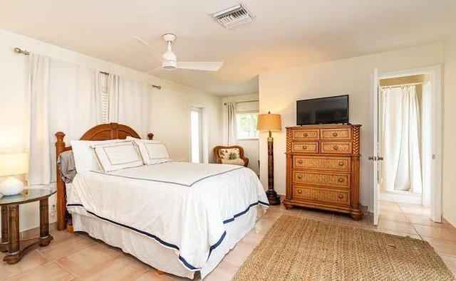 a bedroom with bed a flat tv screen and dresser
