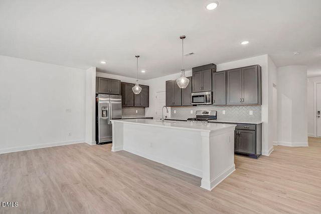 a large kitchen with stainless steel appliances granite countertop a stove a sink and a refrigerator