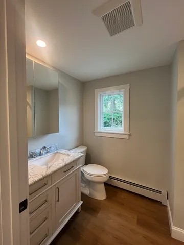 a bathroom with a granite countertop toilet a sink and mirror