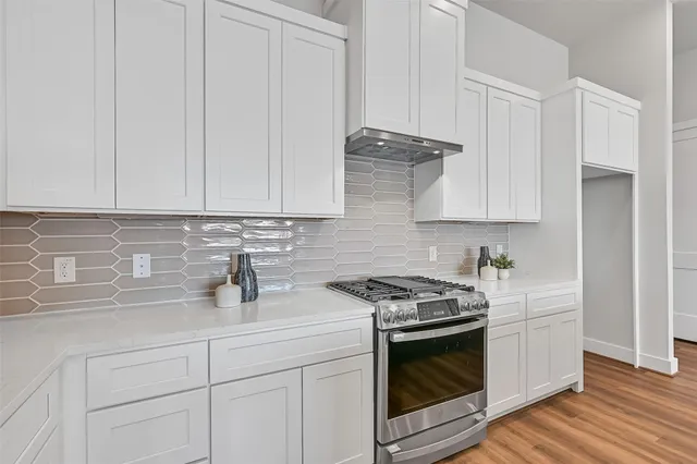 a kitchen with stainless steel appliances granite countertop white cabinets and a stove