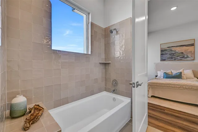 a bathroom with a tub a sink and wooden floor