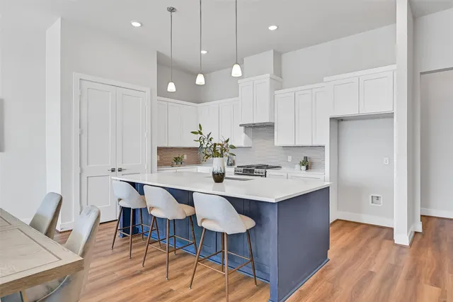 a kitchen with kitchen island a dining table chairs sink and cabinets