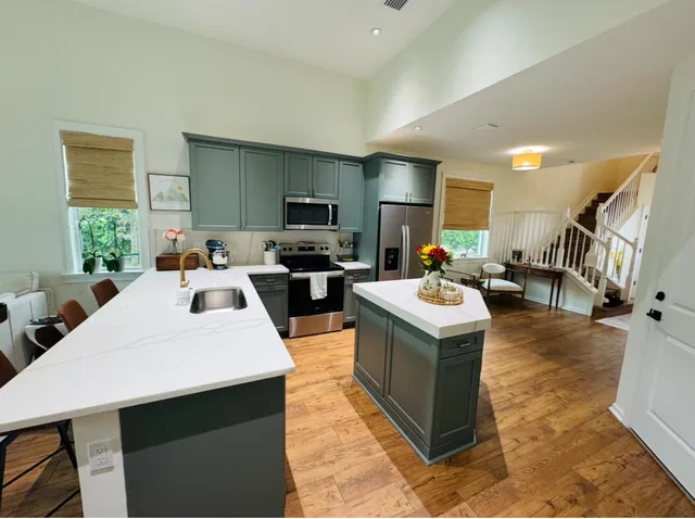 a living room with stainless steel appliances kitchen island granite countertop a table chairs sink a refrigerator and a stove