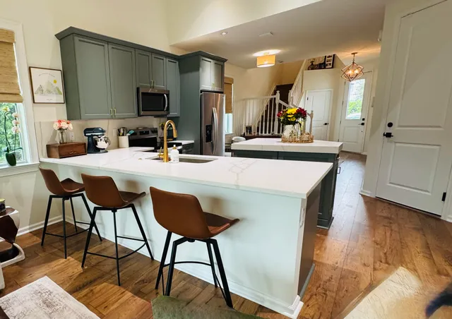 a kitchen with kitchen island a dining table chairs refrigerator and sink