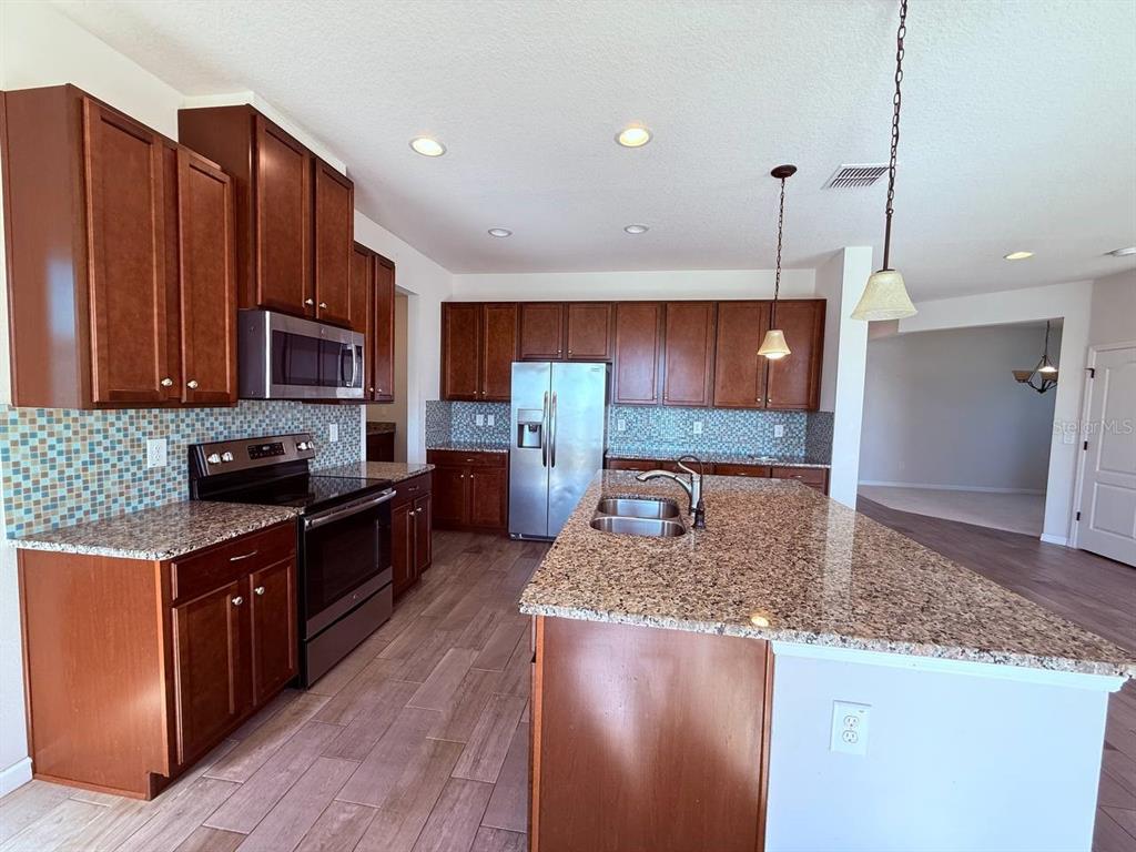 14112 Poke Ridge Drive Riverview, FL 33579 - Photo 7 of 32 a kitchen with stainless steel appliances granite countertop a stove a sink dishwasher a refrigerator and a oven with wooden floor