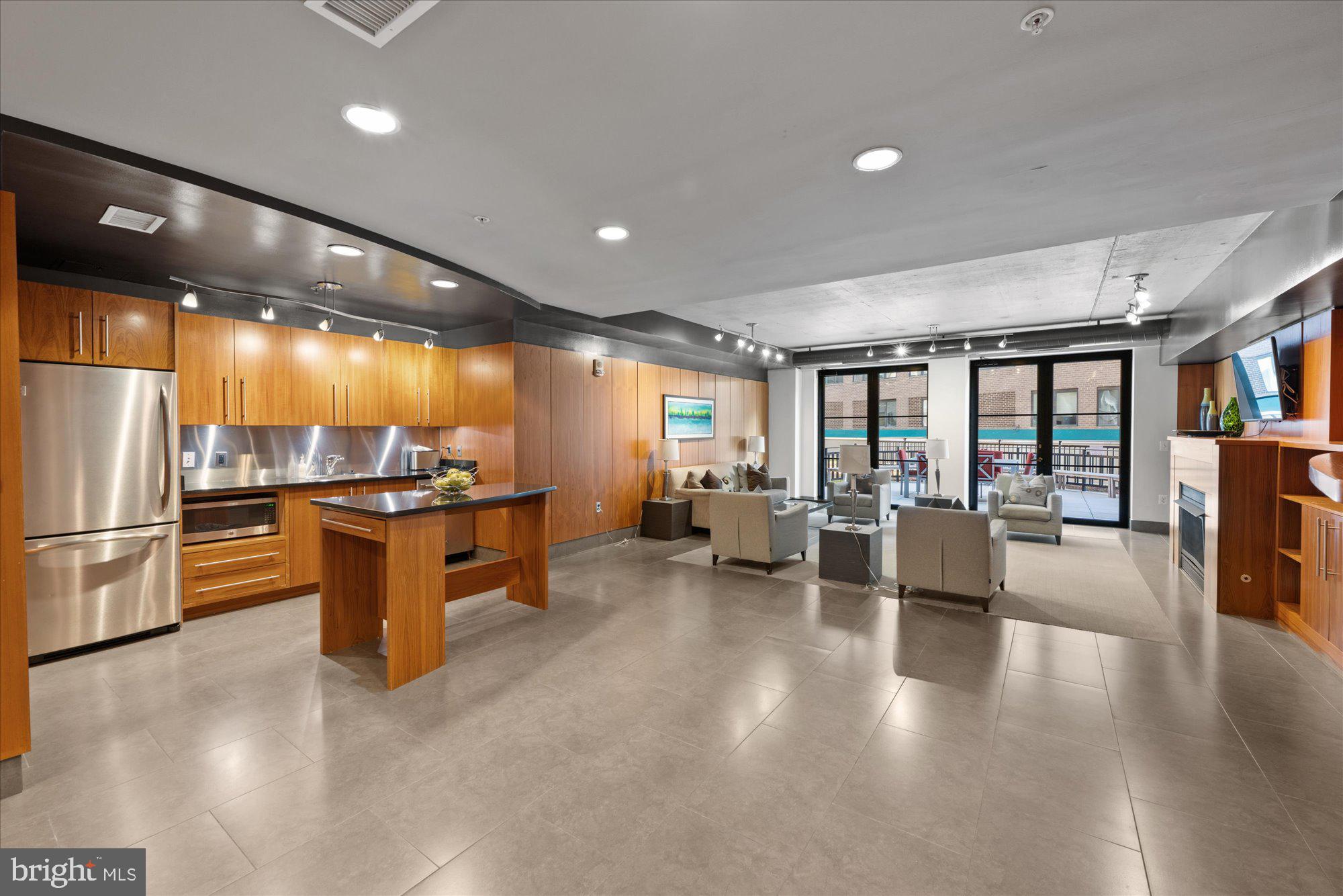1133 14th Street Northwest, Unit 404 Washington, DC 20005 - Photo 12 of 15 a open kitchen with stainless steel appliances kitchen island granite countertop a refrigerator a stove a dining table and chairs with wooden floor