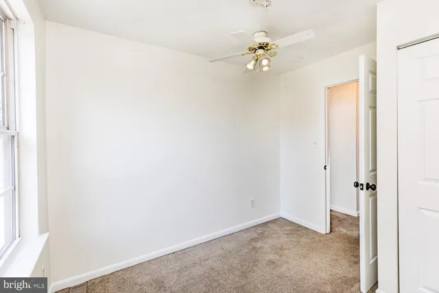 an empty room with a chandelier fan and a window