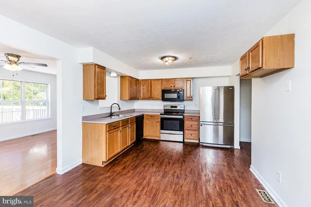 a kitchen with stainless steel appliances a refrigerator and wooden floor