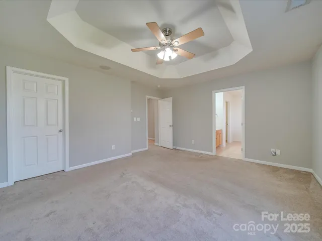 a view of an empty room with chandelier fan