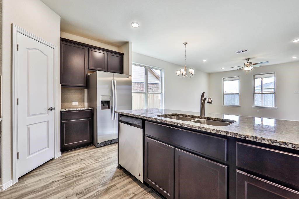 247 Sintra Lk Way Rosenberg, TX 77469 - Photo 10 of 28 a kitchen with granite countertop stainless steel appliances a sink cabinets and wooden floor