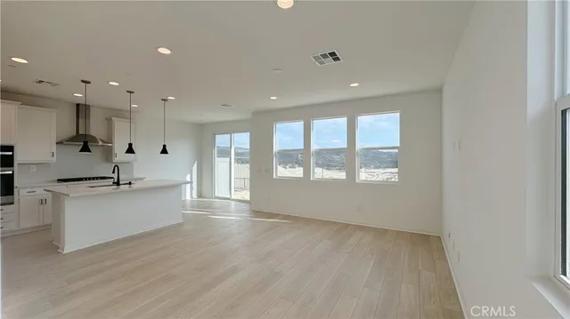 a large kitchen with a large counter top a sink stainless steel appliances and cabinets
