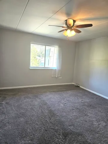 an empty room with a window and a fan