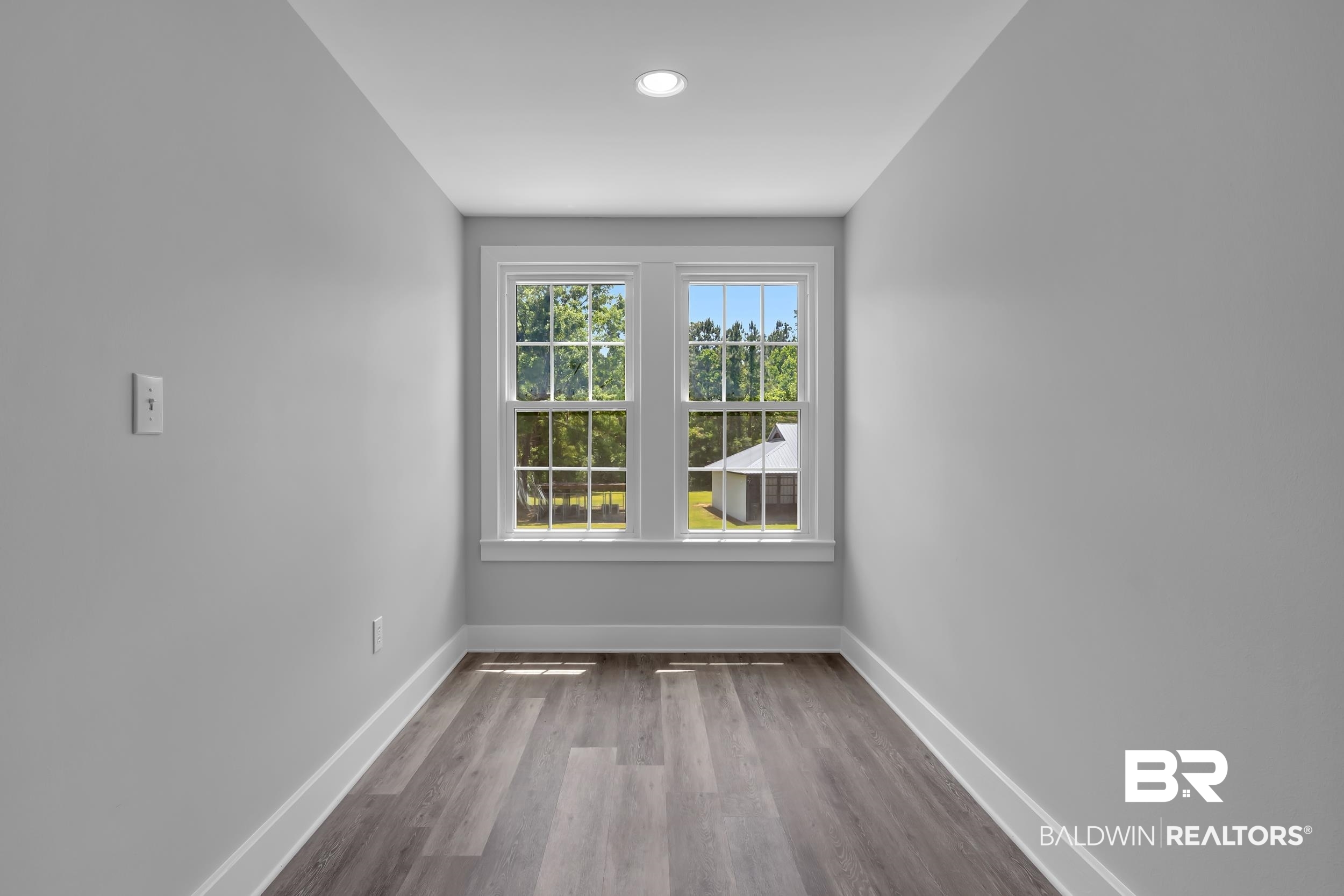 43199 Pine Grove Road Bay Minette, AL 36507 - Photo 66 of 71 Room featuring a pair of double-hung windows, wood-finish flooring, light gray walls, white baseboards, and a recessed ceiling light