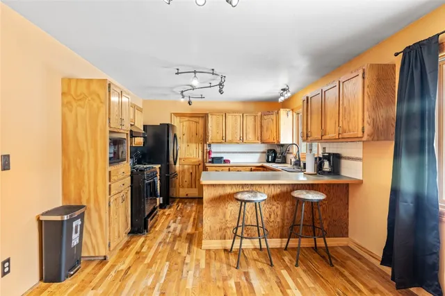 a kitchen with stainless steel appliances a sink dishwasher stove and cabinets with wooden floor