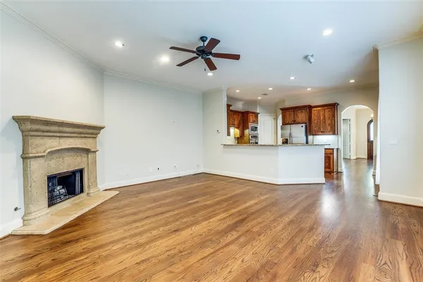 a view of a livingroom with a fireplace a ceiling fan and wooden floor
