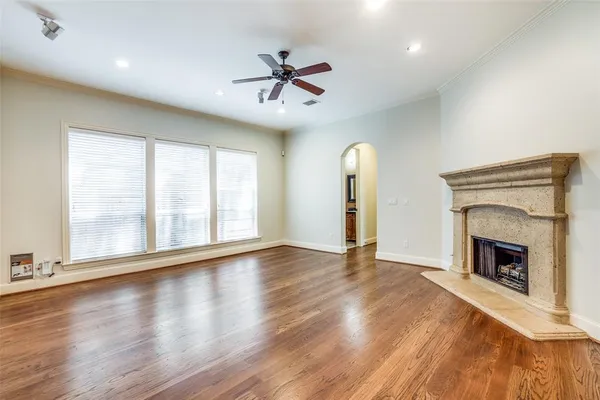 an empty room with wooden floor fireplace and windows