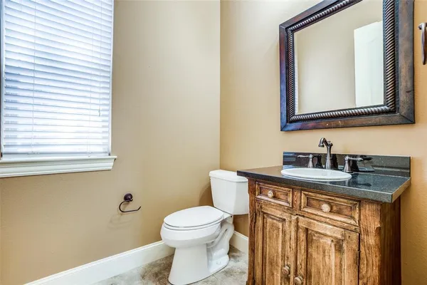 a bathroom with a granite countertop toilet sink and mirror