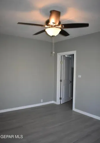 a view of an empty room with wooden floor and a ceiling fan